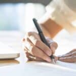 寫作簽名、合約或文件的手部特寫畫面.