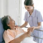 外籍看護師陪伴病人照顧，展現專業醫療服務與溫馨關懷，符合同心協作的精神。.