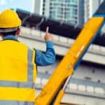 高樓建設工人穿著安全背心與安全帽.