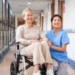 外籍照護員與病患老人微笑交談，展現專業照護服務。.