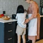 媽媽與孩子在廚房一起烹飪，展現溫馨家庭時光。.