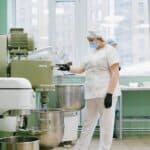 料理工廠工作人員穿戴防護用品操作廚房設備，展現專業外勞技能與食品安全。.