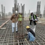 鋼筋施工現場勞動人員和工程師協作檢查施工進度與安全措施.