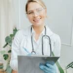 專業醫護人員微笑持病歷冊，展現醫療照護專業與服務熱情.