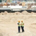 工地施工現場安全檢查，兩名工程師穿著安全帽和背心進行討論，彰顯專業外勞在建築工程中的重要角色.