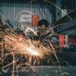 焊接工人在工作現場焊接，火花四散，展現專業技術與國際勞動力合作。.