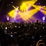 熱鬧的音樂會現場，燈光閃爍，數百名觀眾用手機捕捉精彩瞬間。.