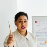 清楚表達的亞洲女性商業講師或演講者，專注於財經與市場分析，展示專業形象，提高外勞集團相關SEO。.