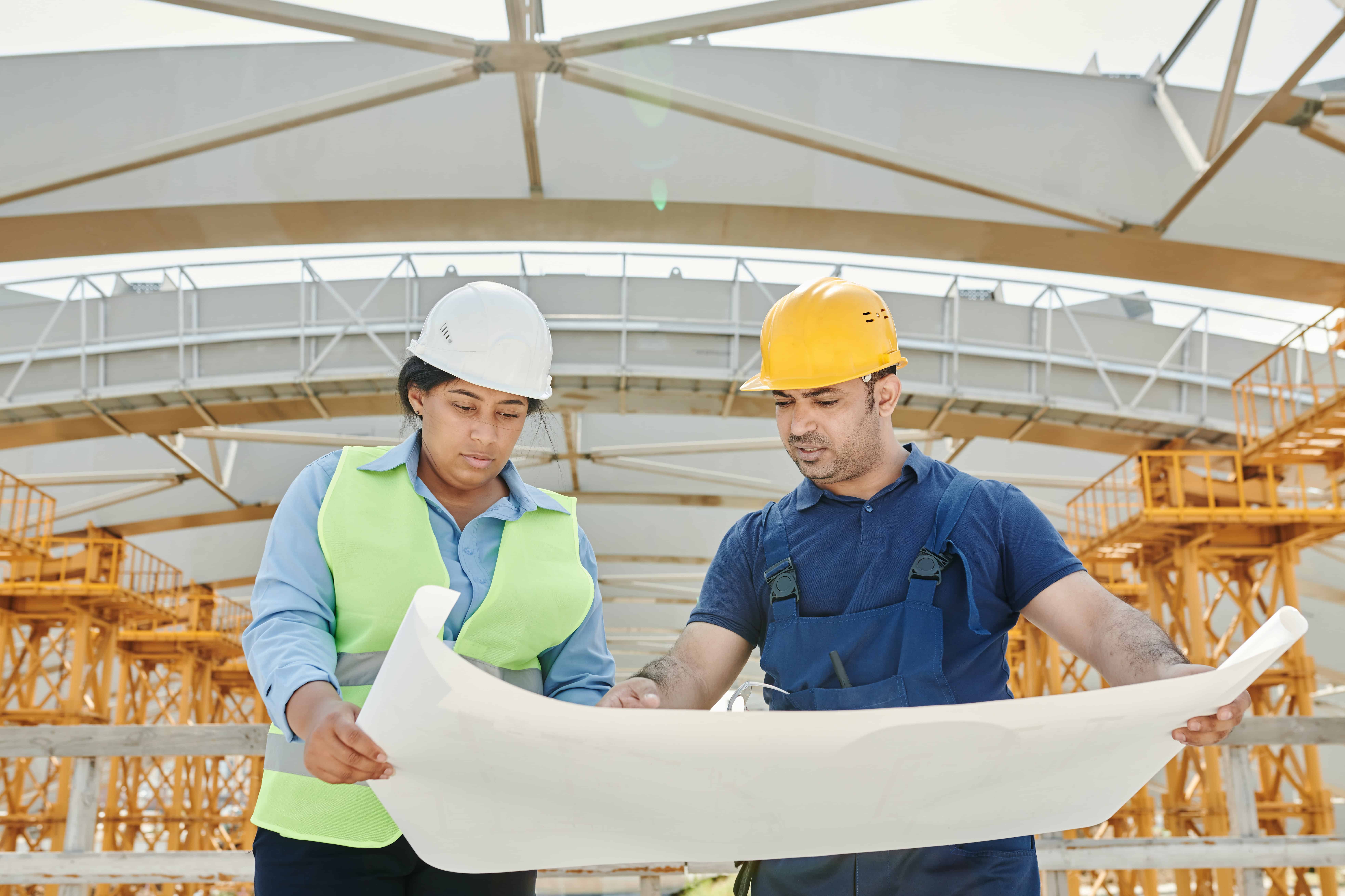 高效施工管理的外勞工程師在建築工地討論藍圖.