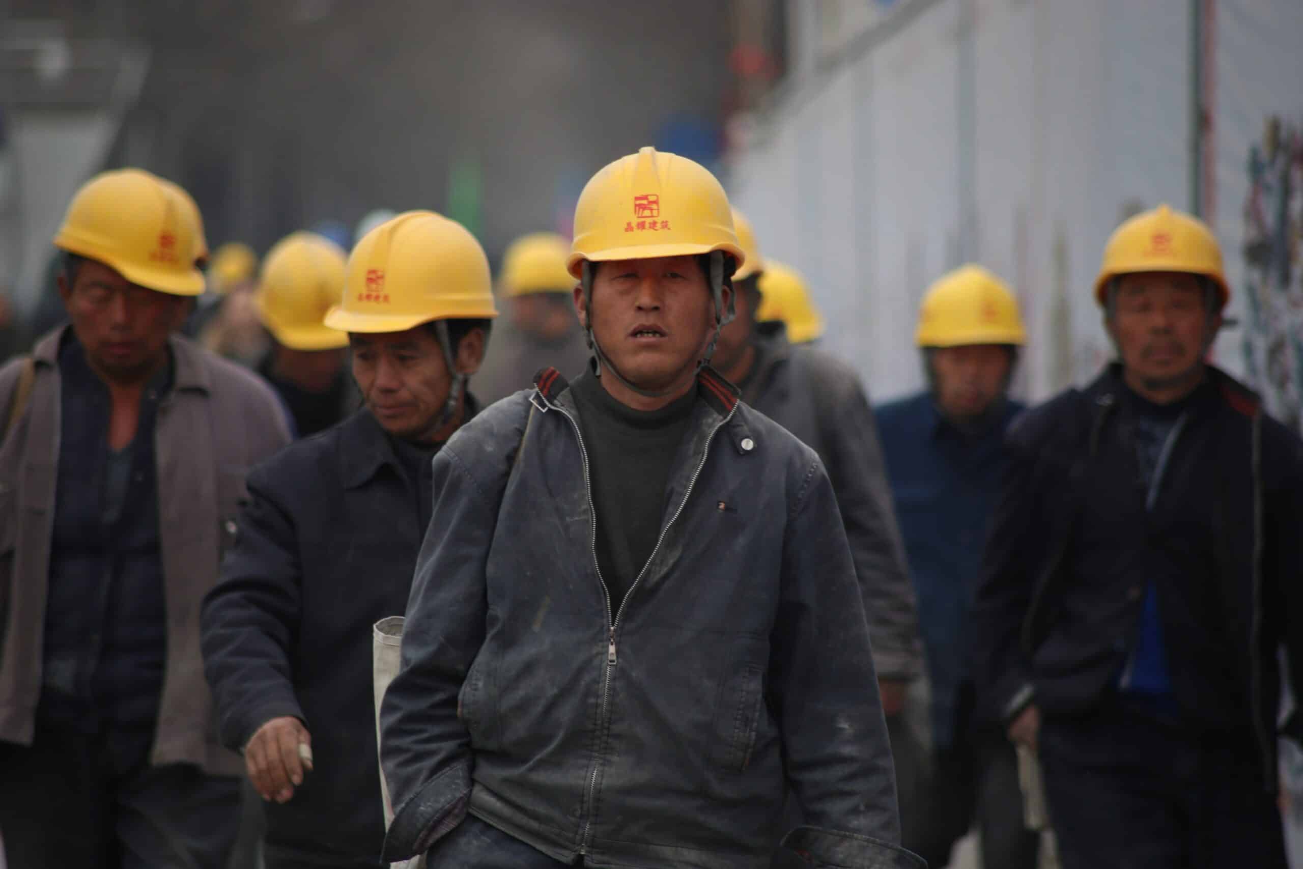 工地工人戴安全帽忙碌，展現21世紀全球外勞集團專業形象。.