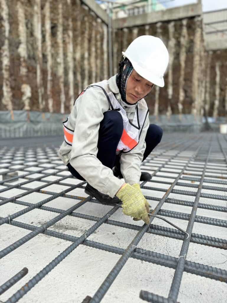 鋼筋施工工人在建築工地進行鋼筋綁扎工作.