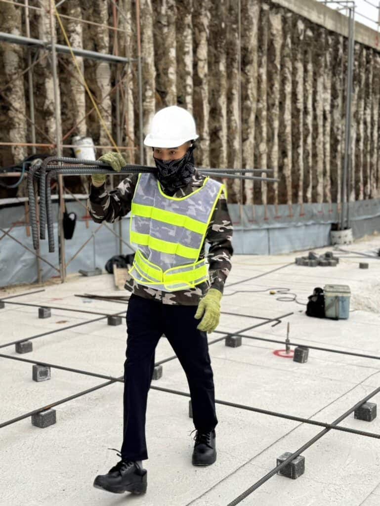 高雄外勞工地施工人員穿著安全背心和安全帽進行建築施工。.