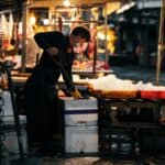 夏季全球外勞集團工作,外勞在夜市攤位清洗食材，展現多元國際人力資源，支持台灣經濟發展。.