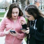 微笑外國女孩使用手機，與朋友共同交流，展現多元文化的社交情景。.