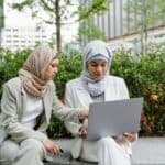 多元文化外勞在公園使用筆記型電腦工作，顯示21世紀全球外勞集團的多國籍合作形象。.