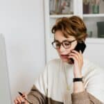 專業女性在辦公室使用手機與筆記本，展現多元外勞及人力資源服務形象.