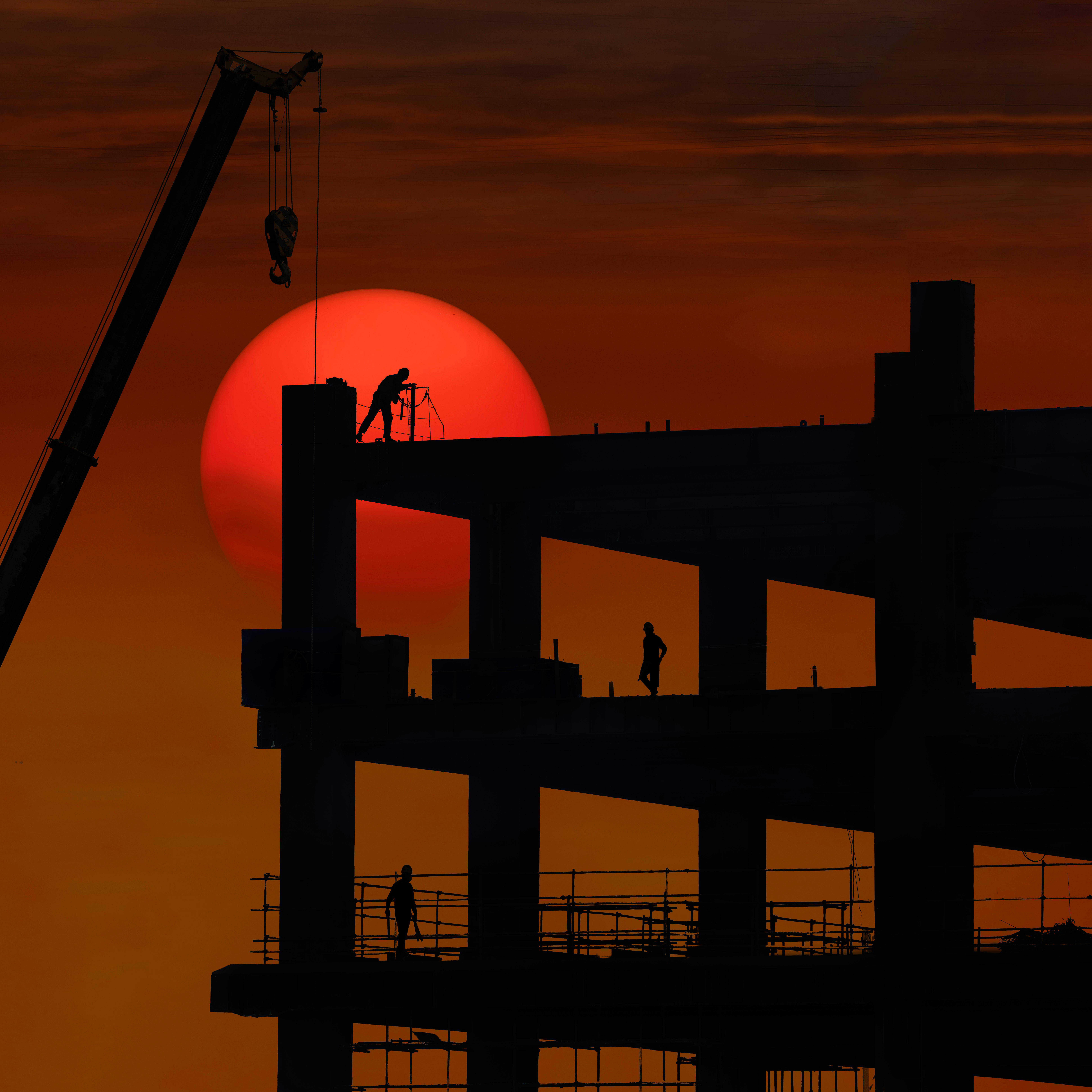 施工現場的建築工人在夕陽下工作，展現外勞的重要角色與敬業精神.