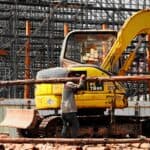 施工工地的工程師使用小型挖掘機進行建築作業，展示21世紀全球外勞集團在國際建設工程中的專業服務。.