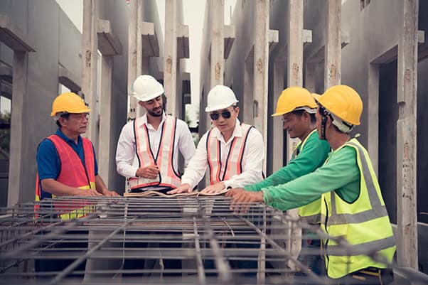 外籍移工|各業大缺工 113 年底移工突破 82 萬人  產業類成長趨勢明顯 一般營造人數倍增 施工現場工人討論建築工程進度與安全措施.