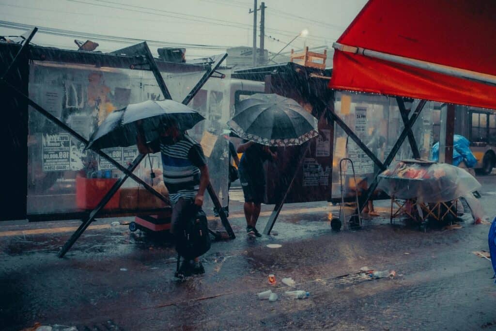 避雨中的街頭場景，展示台灣外勞集團在惡劣天氣中的堅守。.