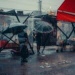 避雨中的街頭場景，展示台灣外勞集團在惡劣天氣中的堅守。.