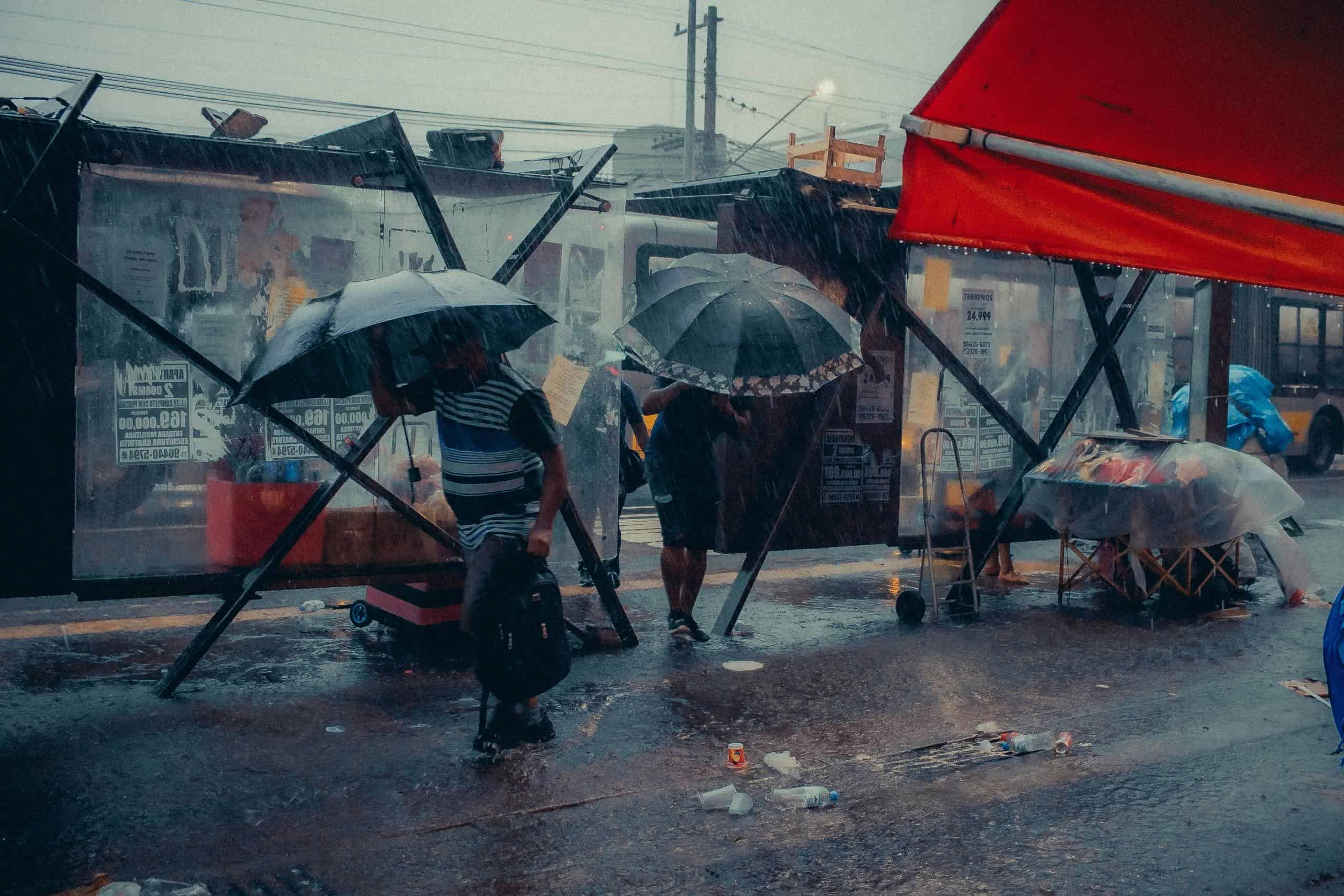 避雨中的街頭場景，展示台灣外勞集團在惡劣天氣中的堅守。.