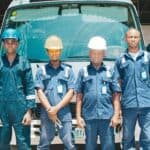 工作人員穿著安全帽站在卡車前，展現專業與團隊合作。.