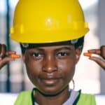 專業外勞工人員佩戴安全帽與耳塞在建築工地上工作，展現全球外勞資源重要性。.