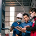 外國技術工人在工廠內進行操作與討論，展示專業技能與合作精神。.