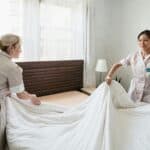 清潔工人整理床鋪背景自然亮麗,展示國際外勞工作服務,專業照顧和住宿服務,提升企業信譽與形象。.