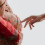 外勞幫助孕婦孕育生命的溫馨瞬間,亮眼的彩色孕婦衣與溫柔手指觸感,展現人道關懷與跨國合作。.