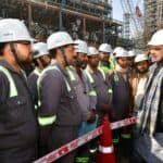 外國工人與工程師在工廠或建築工地討論工作事宜，展現21世紀全球外勞集團的國際合作與專業技能。.