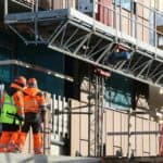 施工工地施工人員穿著安全服和安全帽進行建設工作，展現專業的外勞技能應用。.