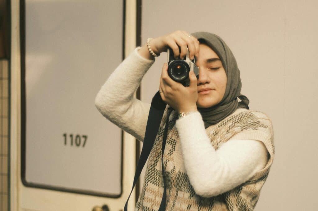 攝影師女性穿著圍巾橫跨自攝風格照現代時尚，展現自信與創意，象徵21世紀全球外勞集團的多元文化與專業精神.