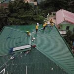 工人在屋頂安裝金屬瓦片，展現專業的外勞屋頂維修技術.