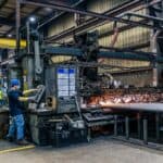 鋼鐵工廠內工人操作大型金屬切割機械，展現專業的工業製造流程和工人的技術力量，彰顯全球外勞集團的專業服務與工業人力資源管理。.